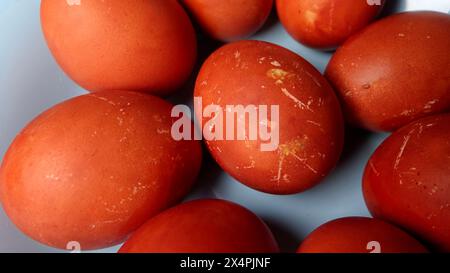 Several textured red and brown Easter eggs neatly arranged on soft blue plate Stock Photo