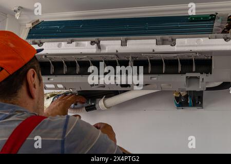 Electrician repairing air conditioner indoors Lviv Ukraine 08.04.24 Stock Photo