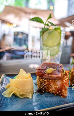 Overhead view of platter of sushi rolls. an appetizing roll on a blue rectangular ceramic plate is served on a table in a restaurant Stock Photo