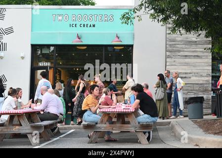 Customers enjoy ice cream on picnic tables outside while a line of people wait to get in the front door at Two Roosters Ice Cream in East Raleigh. Stock Photo