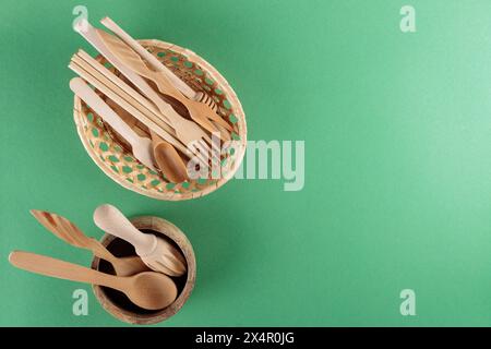 Wooden Kitchen Utensils Collection in Wicker Basket on Green Background, Top View, Copy Space Stock Photo