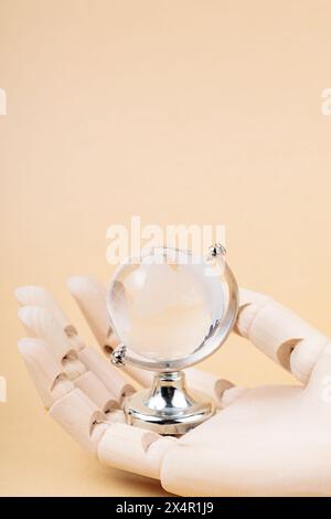 Glass Globe in Cyborg's Palm on Beige Background, Concept of Technological Protection from Environmental Disasters Stock Photo