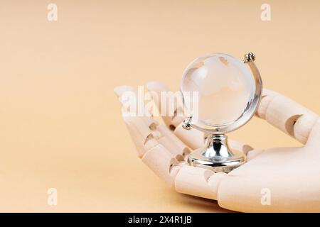 Glass Globe in Cyborg's Palm on Beige Background, Concept of Technological Protection from Environmental Disasters Stock Photo