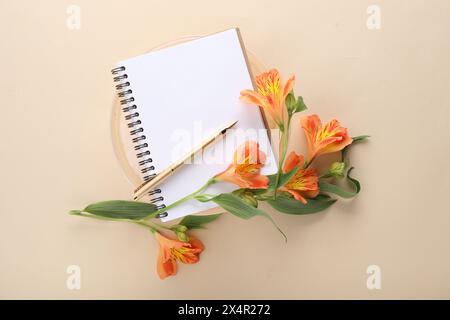 Guest list. Notebook, pen and beautiful flowers on beige background, top view. Space for text Stock Photo