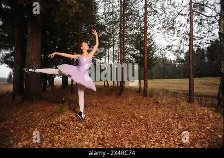 red-haired ballet dancer in sneakers dance among forest Stock Photo