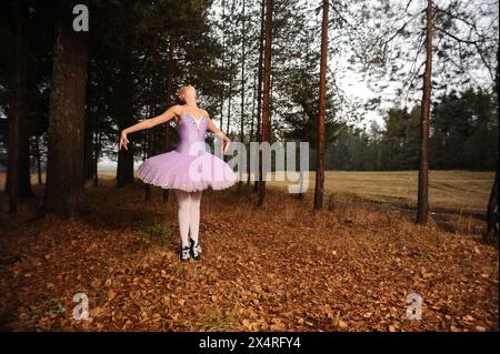 red-haired ballet dancer in sneakers dance among forest Stock Photo