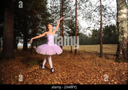 red-haired ballet dancer in sneakers dance among forest Stock Photo