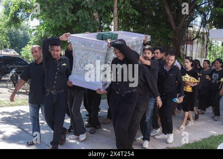 Phatthalung, Thailand- April 05, 2024: Man in black is helping to carry the coffin of the deceased into the crematorium for cremation Stock Photo