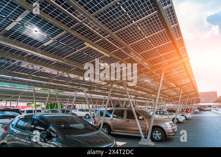 Solar panels installed over parking lot with parked cars for effective generation of clean energy in city. Stock Photo