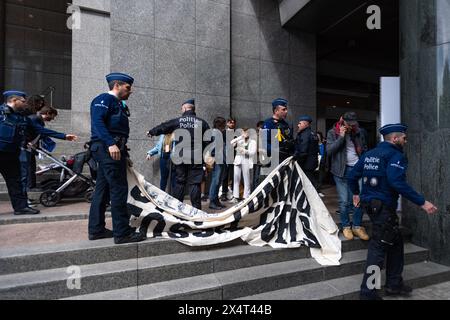 4th May 2024, Brussels, Belgium. Police inspect a banner reading 'Stop Funding Fossil Fuels' while detaining multiple young protesters outside the European Parliament on its public open day. The protesters were then handcuffed and taken away in an unmarked white van. Credit: Alamy Live News Stock Photo