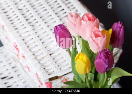 Bouquet of tulips of different colors on a gray background. Near wicker boxes. Stock Photo