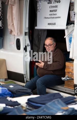 Market stall owner sitting behind counter Stock Photo