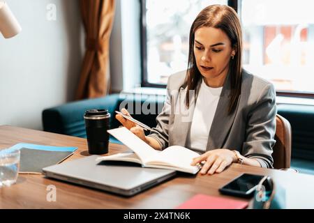 woman working in an office writing in her diary Stock Photo