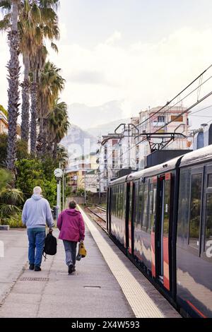 Italy train - a couple on the platform at Sorrento train station catching the local train to Naples;  Sorrento Italy Europe. Stock Photo