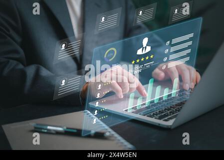 A man is typing on a laptop with a screen displaying a graph of people ratings Employee-KPI Dashboard. HR human resources Analytics and CRM Stock Photo