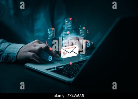 A person's hands are shown typing on a laptop, surrounded by digital email icons of documents and a warning sign. The image conveys a sense of urgency Stock Photo