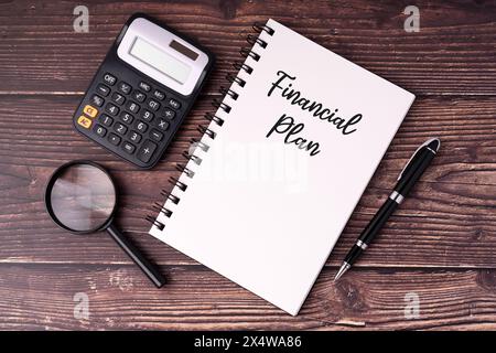 Financial plan text on notepad, pen, calculator, magnifying glass flat lay Stock Photo