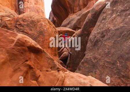 Young Hiker Boy Climbing through the Narrow Path in Fiery Furnace in Arches National Park, Utah, United States. Stock Photo