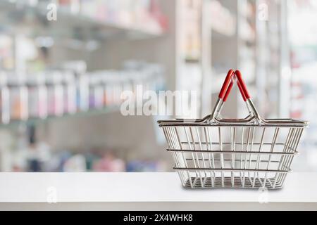 Empty shopping basket on pharmacy drugstore counter with blur shelves of medicine and vitamin supplements background Stock Photo