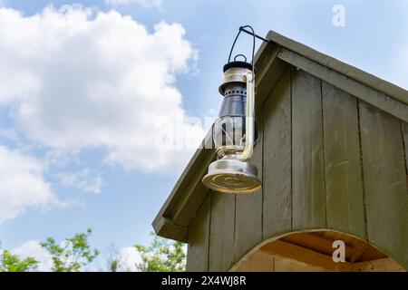 An old kerosene lamp hung from a green wooden guard booth Stock Photo
