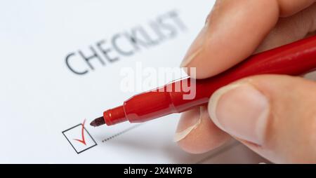 red marker ticking off a checkbox on a checklist Stock Photo