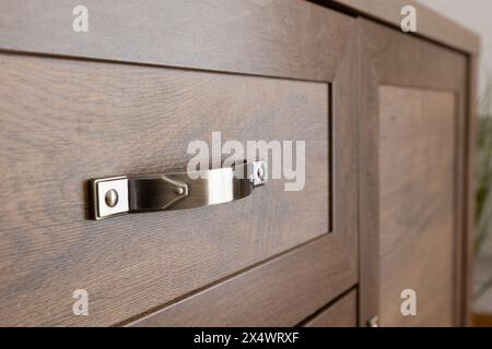 Metal handle on brown drawer, interior of the house room, close-up Stock Photo