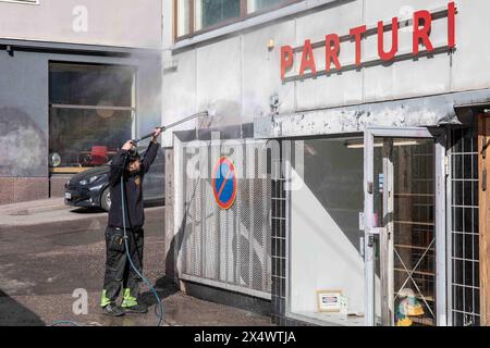 Maintenance man removing graffiti from the wall with a pressure washer at Fleminginkatu 19 in Harju district of Helsinki, Finland Stock Photo