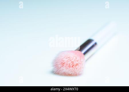 Close-up view of a makeup brush with pink bristles and a white handle on a clean white table Stock Photo