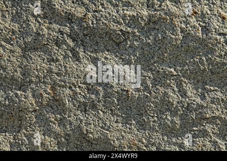 Grey uneven wall, texture, background. Relief rocky and shady surface of granite stone. Roug volcanic rock of light-grey color. Uneven backdrop Stock Photo