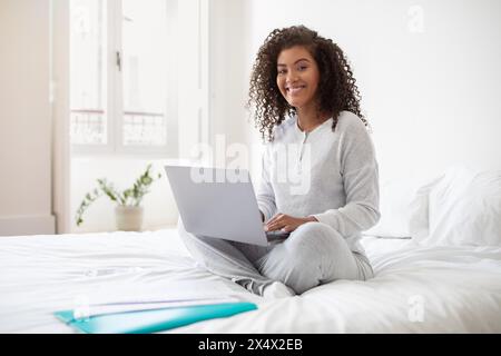 Woman Sitting on Bed Using Laptop Computer Stock Photo