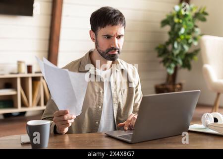 Distressed Man Working on Laptop at Table Stock Photo