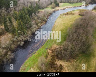 The Pirita River flows through the forest in spring, photo from a drone in cloudy weather. Nature of Estonia. Stock Photo