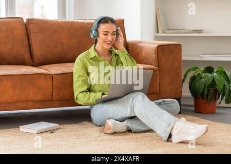 Young Woman Enjoying Music While Working on Laptop at Home Stock Photo