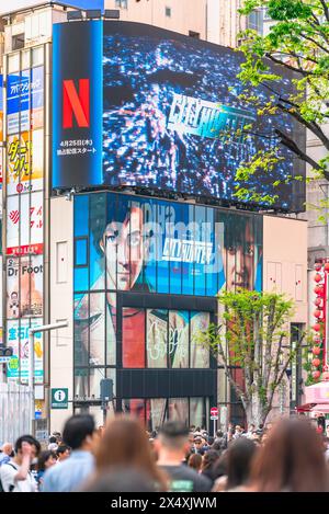 tokyo, japan - apr 28 2024: Crowd walking towards the poster of the Netflix movie 'City Hunter' or 'Nicky Larson' under the movie trailer displayed on Stock Photo