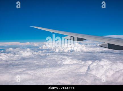 View from aeroplane window of puffy clouds and bright blue sky with ...