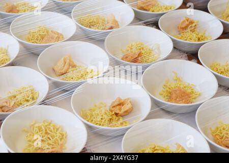 Several white bowls containing yellow noodles, fried foods and meatballs without sauce on the table Stock Photo