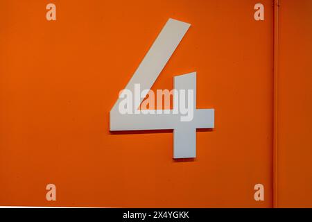 Floor level 4 in a parking ramp, garage, car parking with a large white number on an orange background. Stock Photo