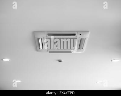 Ceiling mounted cassette type air conditioner decoration near ceiling lights on white building interior. Ceiling type of air conditioning unit with ve Stock Photo
