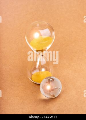 Environmental sustainability, time and responsibility, conserve resources, save planet concept. Small glass world globe near hourglass isolated on min Stock Photo