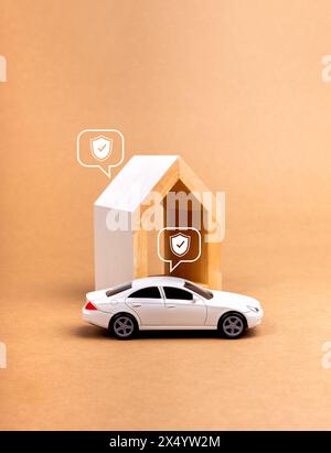 Home and car insurance concept. Shield icon in speech bubbles on white toy car and modern house model isolated on minimal brown background, vertical s Stock Photo