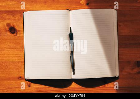 Journal or diary with blank mockup pages and a pen on the desk, top view Stock Photo