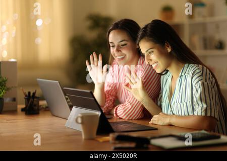 Two happy tele workers having videocall in the night at home Stock Photo