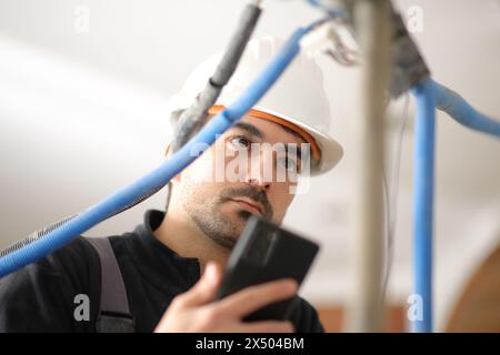 Electrician checking installation using phone in a house under construction Stock Photo