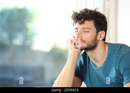 Satisfied man relaxing near a window at home Stock Photo