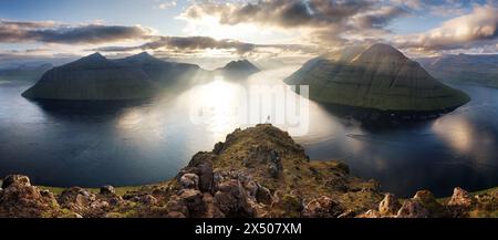 Silhouette of man over dramatic sunset with mountain and ocean in Faroe islands near Klaksvik Stock Photo