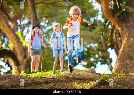 Kids explore nature. Children hike in sunny summer park. Scout club and science outdoor class. Boy and girl watch plants through magnifying glass. Stock Photo
