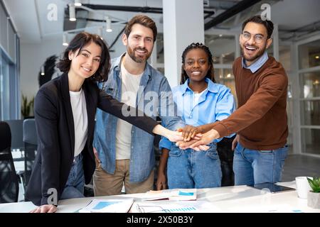 Happy diverse businesspeople collaborating on new project holding hands in boardroom Stock Photo