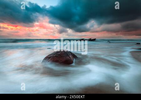 Stormy sunset over rough sea and rocky beach, Lithuania Stock Photo