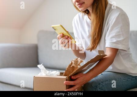 Shopping at home, unpacking a delivered package and posting a photo of the purchase on social networks. Stock Photo