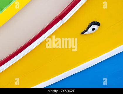 An abstract view of the bright stripes and the eye symbol of a traditional Maltese Luzzu fishing boat in Marsaxlokk harbour, Malta. Stock Photo